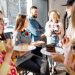 A group of co-workers enjoying food and drinks together at a lively event.